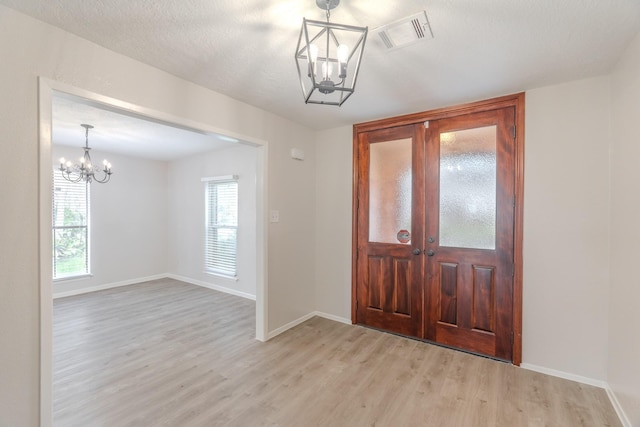 foyer with a chandelier, light hardwood / wood-style floors, and a textured ceiling