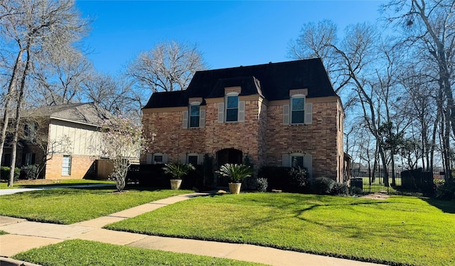 view of front of house featuring a front lawn, fence, and brick siding