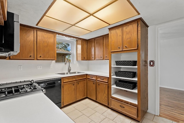 kitchen with black dishwasher, sink, light tile patterned floors, and stainless steel gas range