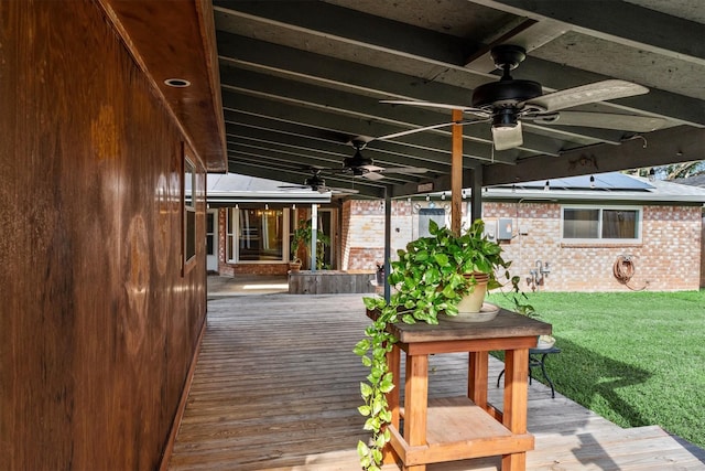 wooden terrace featuring ceiling fan and a lawn