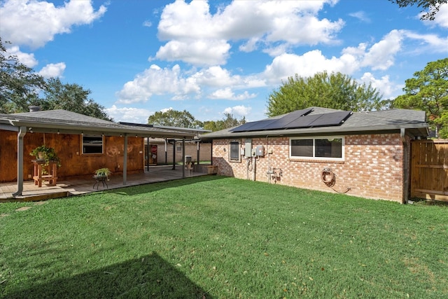 rear view of property with a yard, a patio, and solar panels