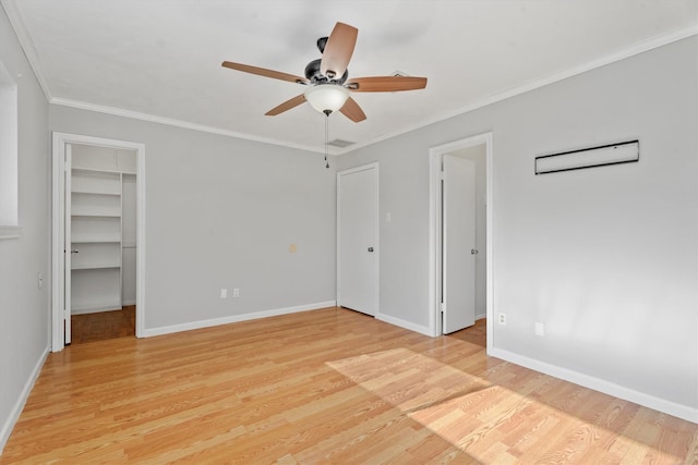 unfurnished bedroom featuring a spacious closet, ornamental molding, light hardwood / wood-style floors, and ceiling fan