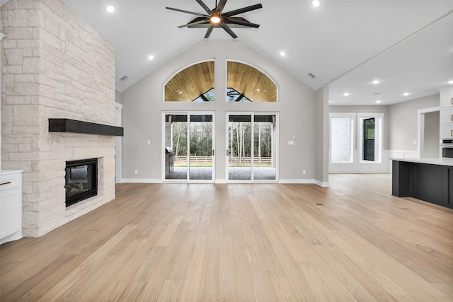 unfurnished living room with ceiling fan, high vaulted ceiling, a fireplace, and light hardwood / wood-style floors