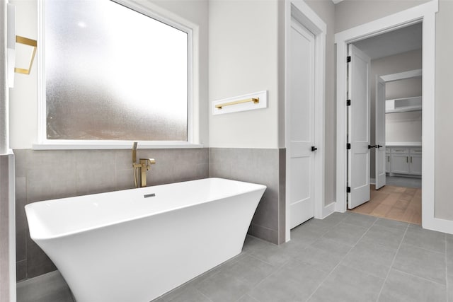 bathroom featuring a healthy amount of sunlight, tile patterned flooring, and a washtub