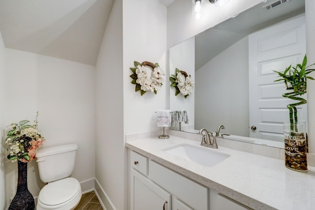 bathroom with lofted ceiling, toilet, and vanity