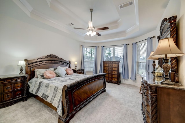 carpeted bedroom with a raised ceiling, crown molding, and ceiling fan