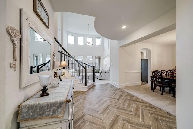 entryway with a towering ceiling, parquet floors, and ceiling fan