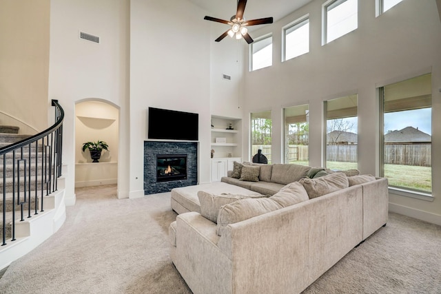 living room with light colored carpet, built in features, and ceiling fan