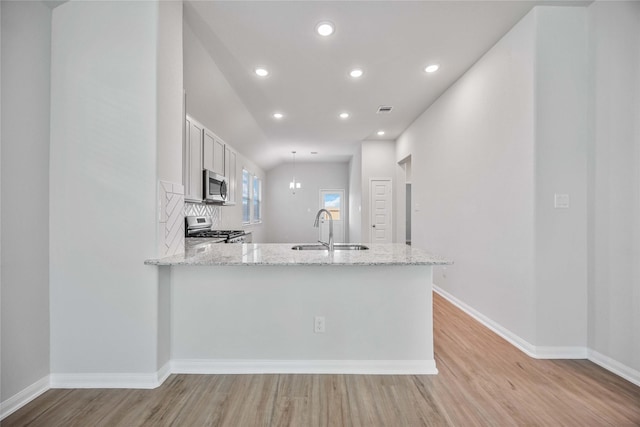 kitchen featuring sink, white cabinetry, light stone counters, kitchen peninsula, and stainless steel appliances