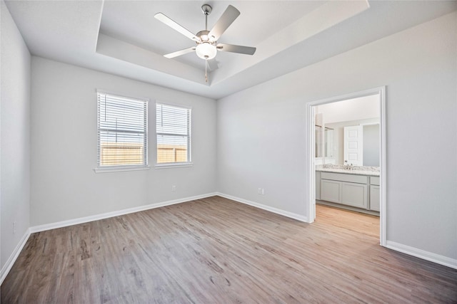 unfurnished room featuring light hardwood / wood-style floors, a raised ceiling, and ceiling fan