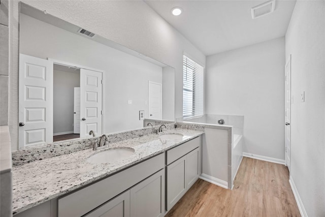 bathroom with hardwood / wood-style flooring, vanity, and a washtub