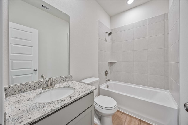 full bathroom featuring vanity, wood-type flooring, toilet, and tiled shower / bath