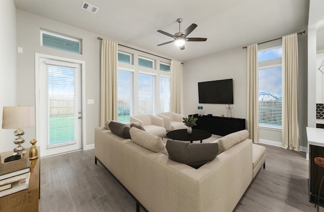 living room featuring ceiling fan, wood-type flooring, and a healthy amount of sunlight