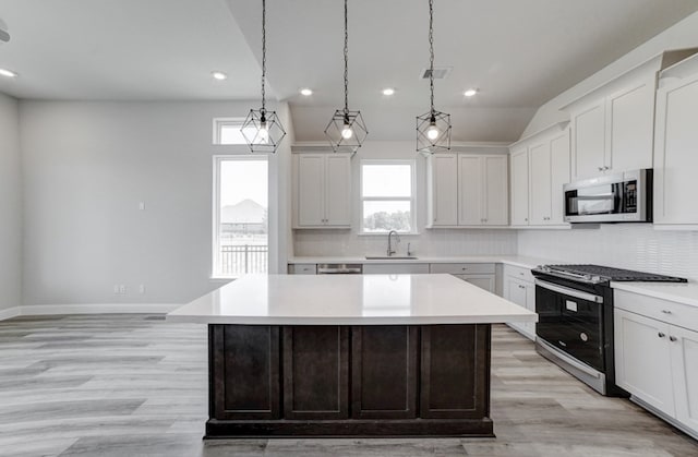 kitchen with white cabinetry, stainless steel appliances, a center island, and sink