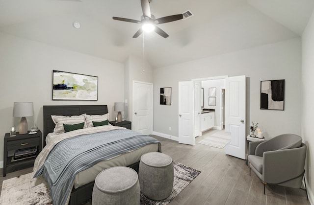 bedroom with ceiling fan, lofted ceiling, ensuite bathroom, and wood-type flooring