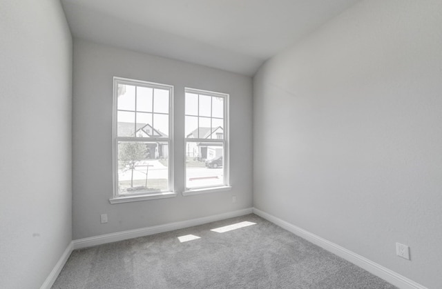 carpeted spare room with vaulted ceiling