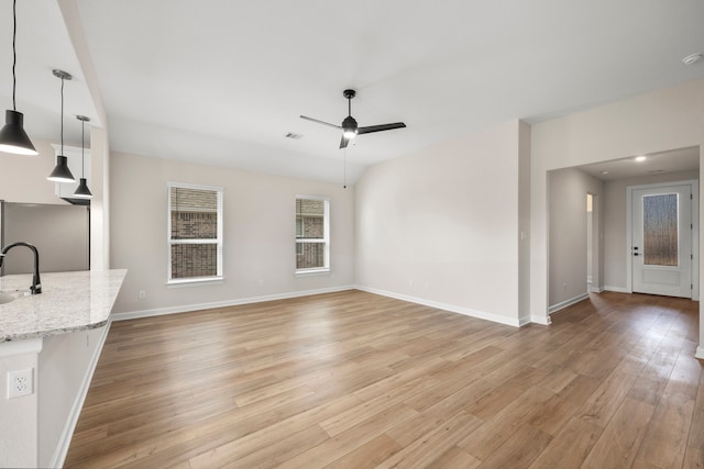 unfurnished living room featuring sink, light hardwood / wood-style flooring, and ceiling fan