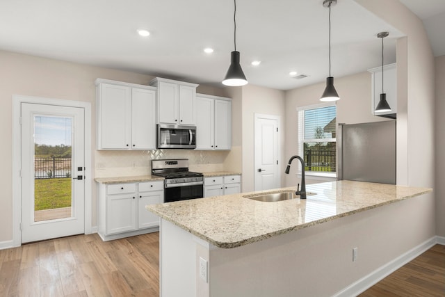 kitchen with sink, white cabinetry, light stone counters, hanging light fixtures, and appliances with stainless steel finishes