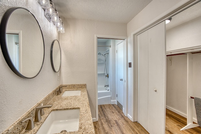 bathroom with vanity, hardwood / wood-style floors, a textured ceiling, and washtub / shower combination