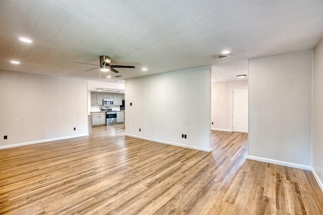 unfurnished living room with ceiling fan, light hardwood / wood-style flooring, and a textured ceiling