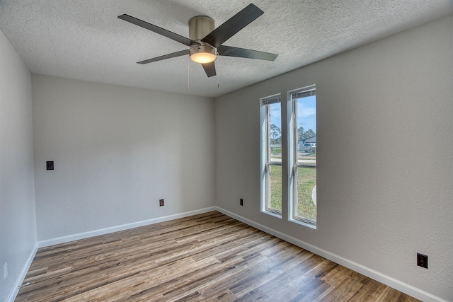 spare room with ceiling fan, a wealth of natural light, light hardwood / wood-style floors, and a textured ceiling