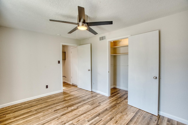 unfurnished bedroom featuring ceiling fan, a textured ceiling, light hardwood / wood-style floors, and a closet