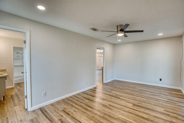 unfurnished room with ceiling fan, a textured ceiling, and light wood-type flooring