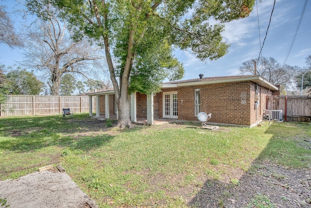 rear view of property with central AC, a lawn, and french doors