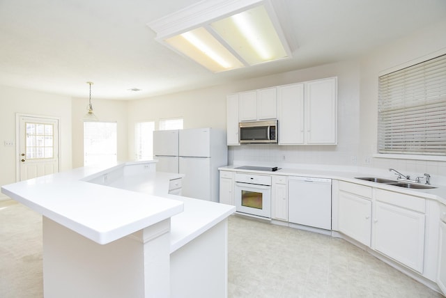 kitchen featuring sink, white appliances, hanging light fixtures, white cabinets, and a kitchen island