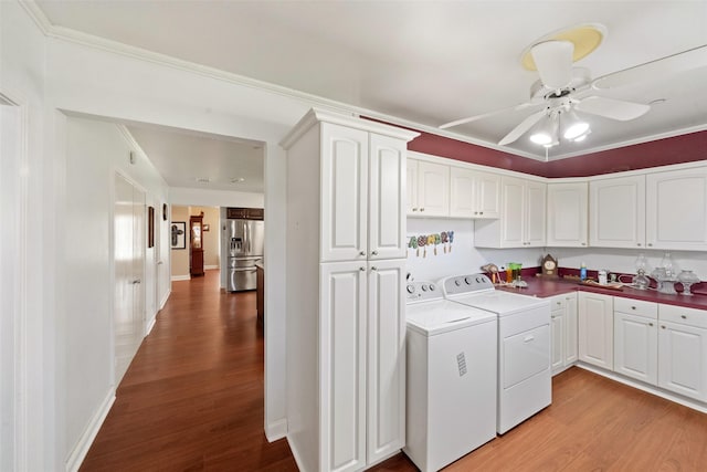 laundry room featuring ceiling fan, cabinets, ornamental molding, washing machine and clothes dryer, and light wood-type flooring