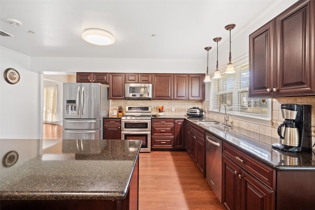 kitchen featuring dark stone countertops, sink, stainless steel appliances, and light hardwood / wood-style floors