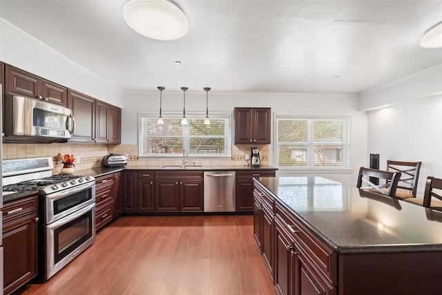 kitchen featuring tasteful backsplash, sink, hanging light fixtures, stainless steel appliances, and dark wood-type flooring