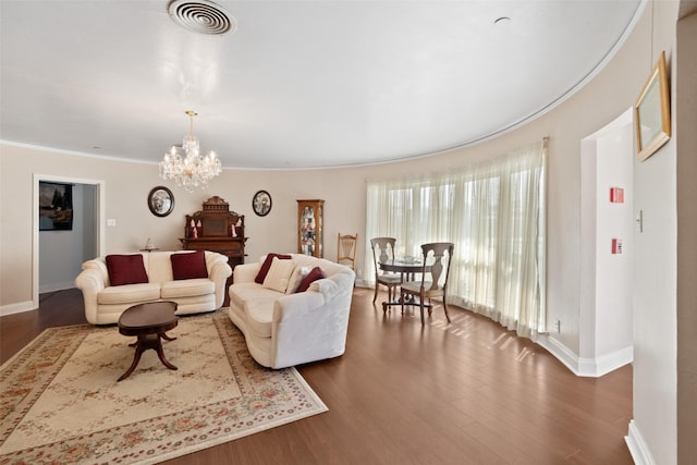 living room featuring dark hardwood / wood-style flooring, ornamental molding, and a chandelier