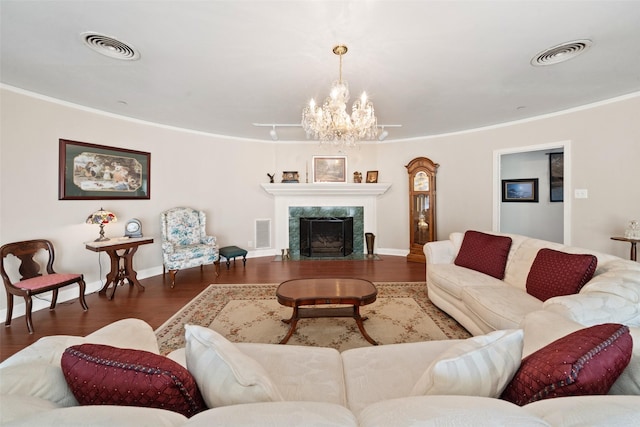 living room with crown molding, dark wood-type flooring, a chandelier, and a fireplace