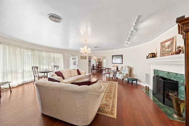 living room featuring an inviting chandelier, a premium fireplace, track lighting, and dark hardwood / wood-style flooring