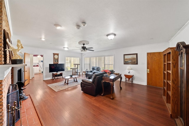 living room featuring ceiling fan, a fireplace, hardwood / wood-style floors, and a textured ceiling