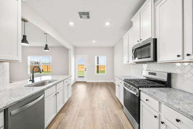 kitchen featuring stainless steel appliances, light stone countertops, sink, and white cabinets