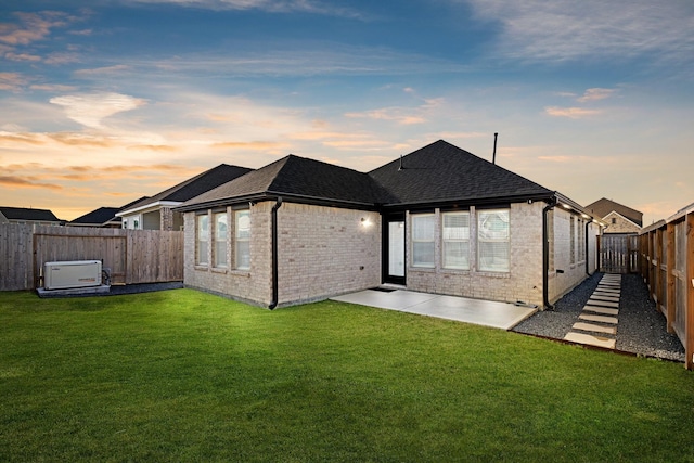 back house at dusk featuring a yard and a patio