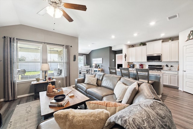 living room featuring vaulted ceiling, dark hardwood / wood-style floors, and ceiling fan