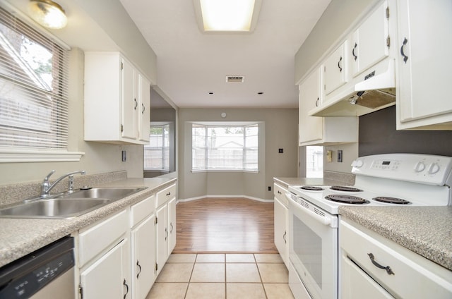 kitchen featuring electric stove, light countertops, a sink, and white cabinets