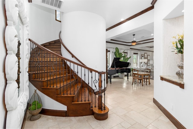 stairway with ornamental molding, a tray ceiling, visible vents, and baseboards