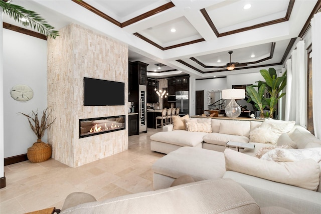 living area featuring beam ceiling, crown molding, a fireplace, a ceiling fan, and coffered ceiling