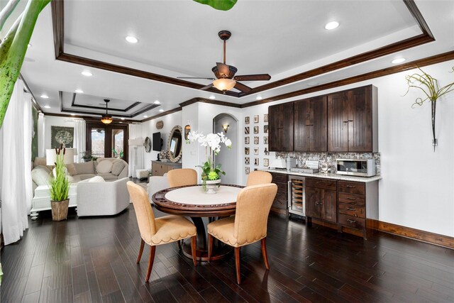 dining area featuring a ceiling fan, a raised ceiling, beverage cooler, and dark wood-style flooring