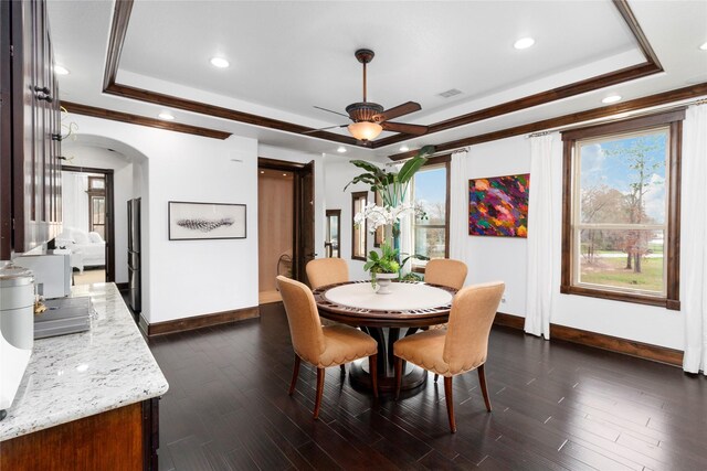 dining room featuring dark wood-style floors, visible vents, arched walkways, and a raised ceiling