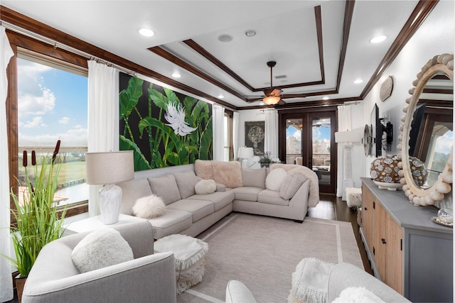 living area with plenty of natural light, ornamental molding, a raised ceiling, and french doors