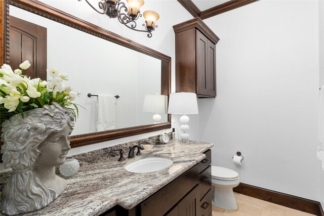 bathroom featuring toilet, vanity, baseboards, an inviting chandelier, and crown molding