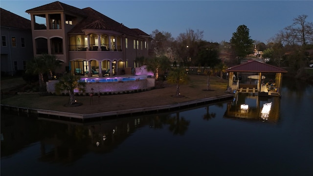 rear view of house with a water view, boat lift, and an outdoor pool