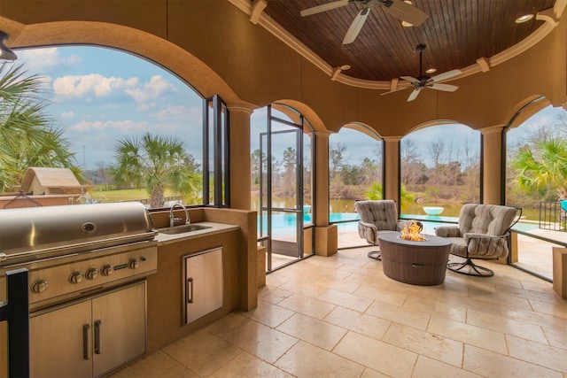 view of patio with an outdoor fire pit, a sink, a ceiling fan, exterior kitchen, and an outdoor pool