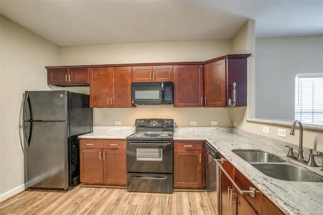 kitchen featuring sink, light hardwood / wood-style flooring, light stone counters, and black appliances