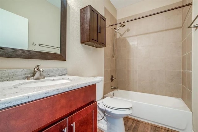 full bathroom featuring vanity, wood-type flooring, toilet, and tiled shower / bath